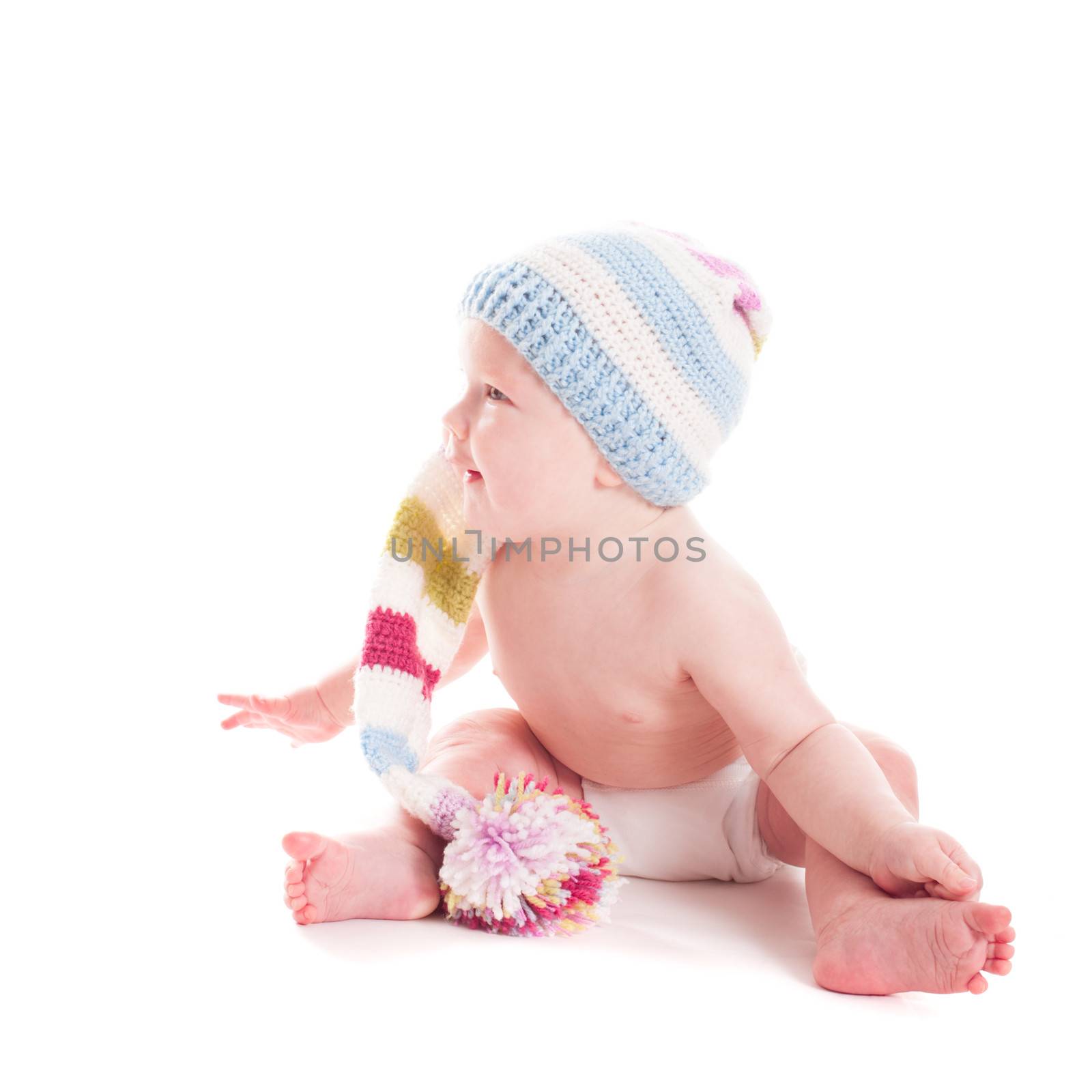 Adorable 6 month baby in crochet hat looks away, on white