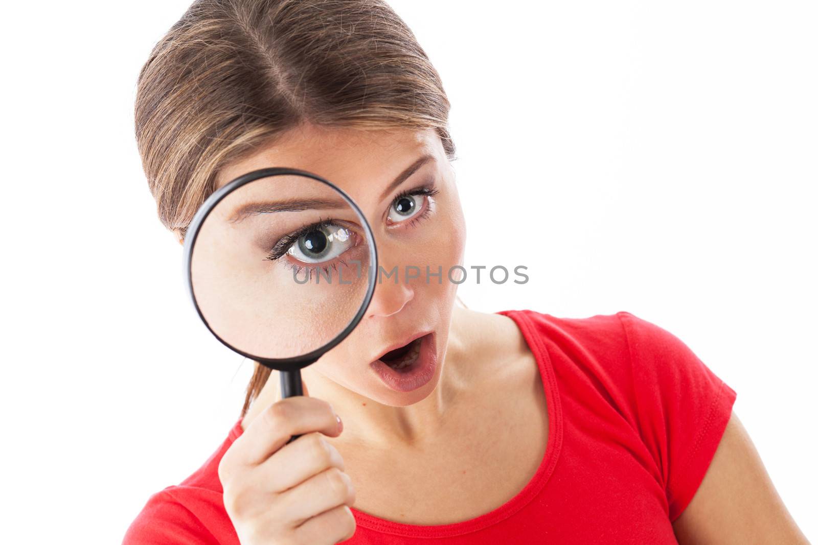 Girl looking through a magnifying glass and looking surprised, isolated on white