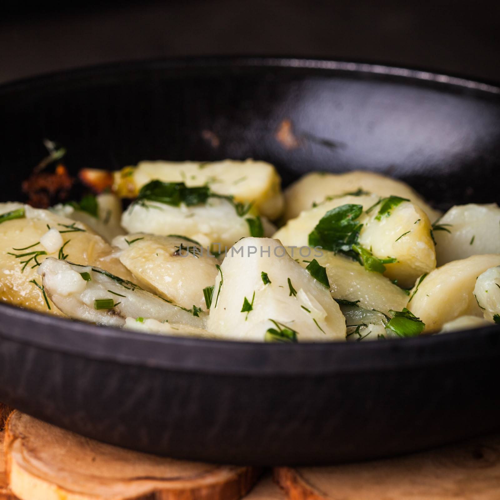 Rustic baked potato with herbs in frying pan