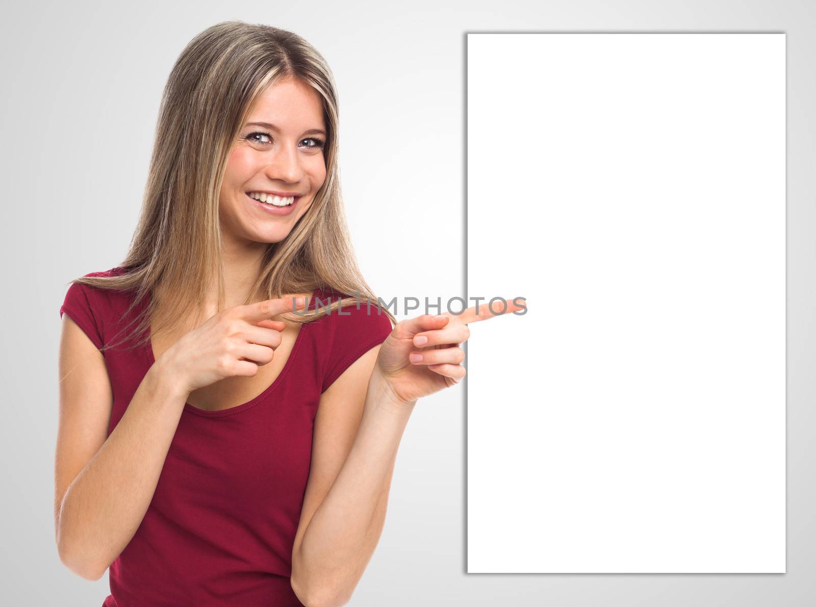 Cheerful young woman showing a white signboard with her hands