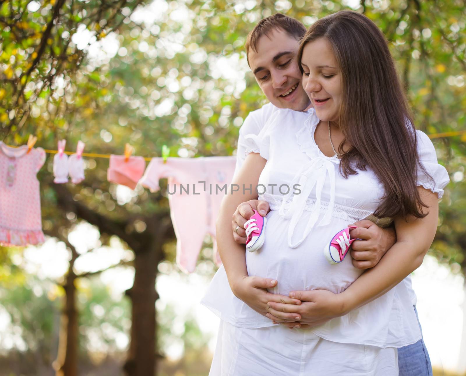Pregnant couple with baby wear, waiting for girl
