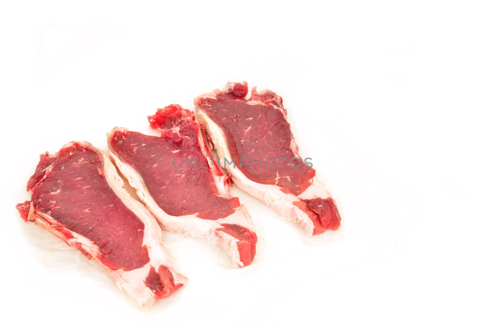 three Spanish beef steaks on paper isolated  by Carche
