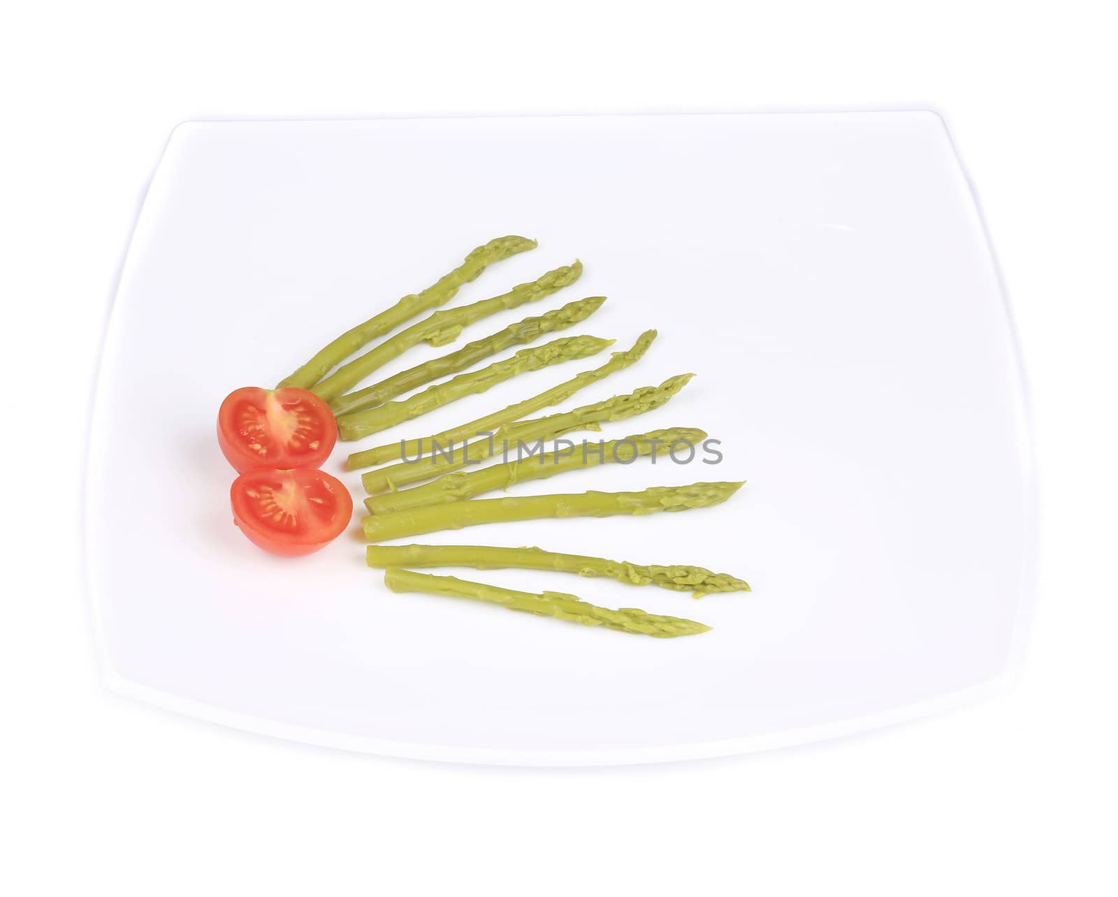 Green asparagus and cherry tomatoes on a plate. Isolated on a white background.