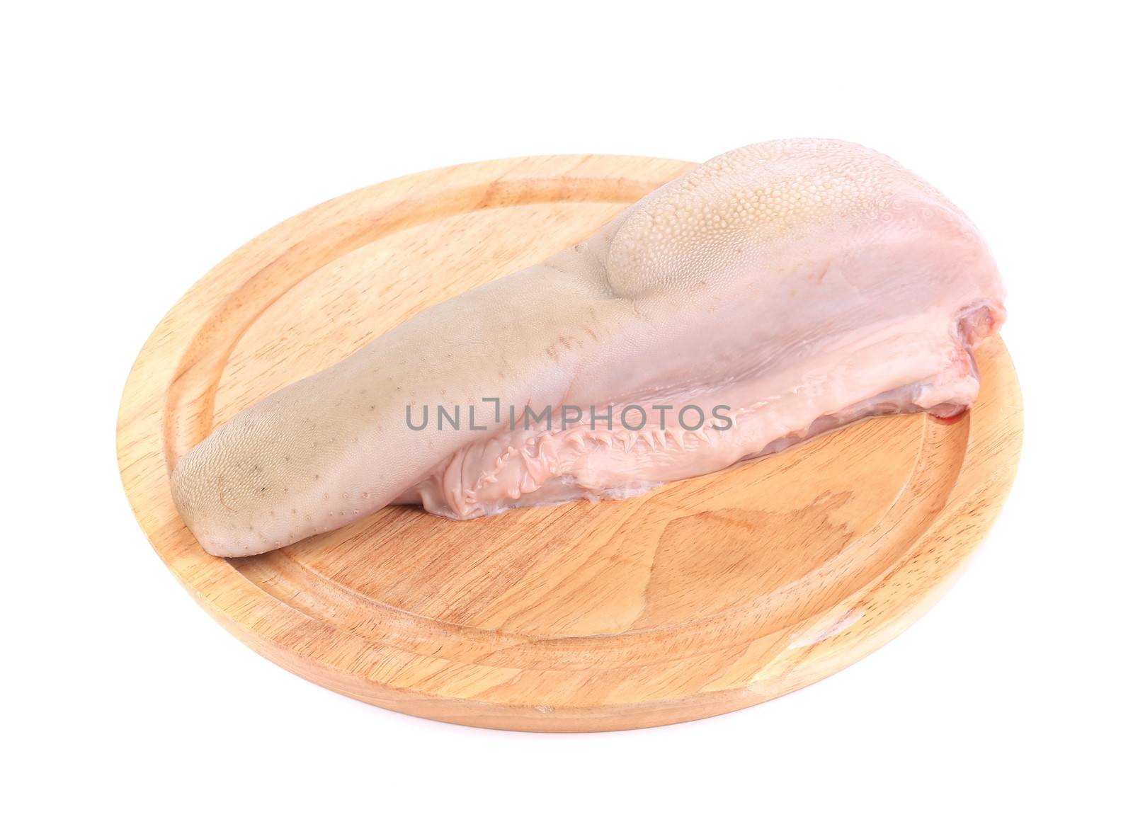 Raw cow tongue on wooden platter. Isolated on a white background.