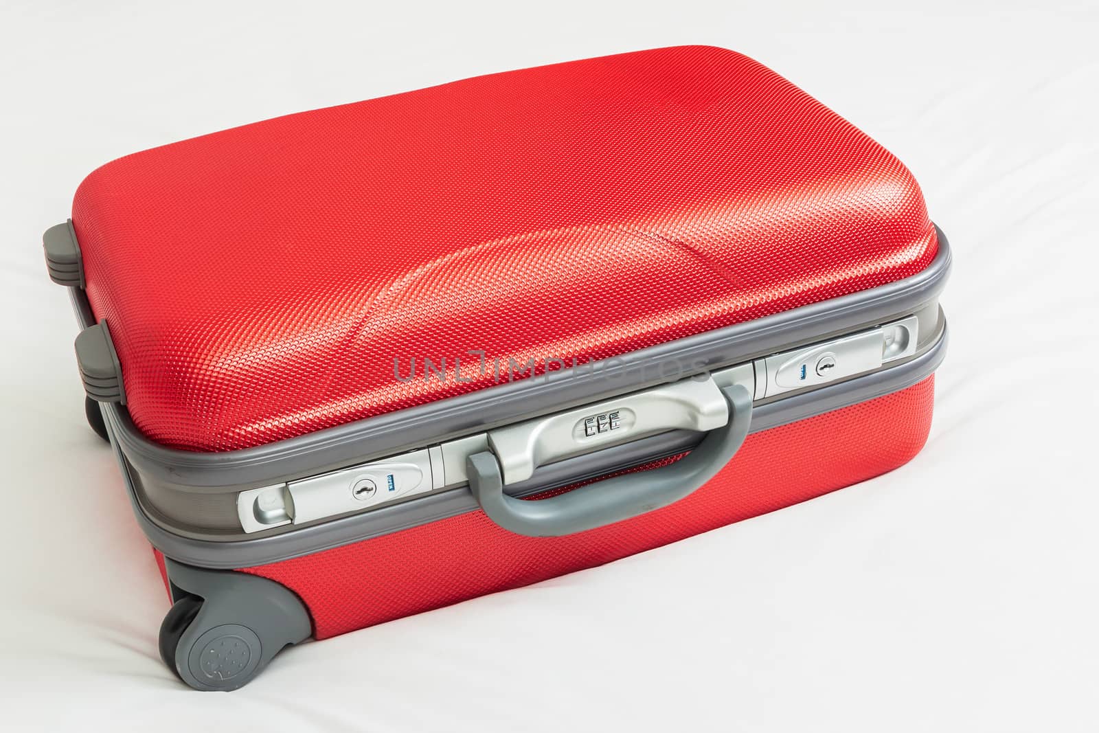 business suitcase, red color on bed for traveling