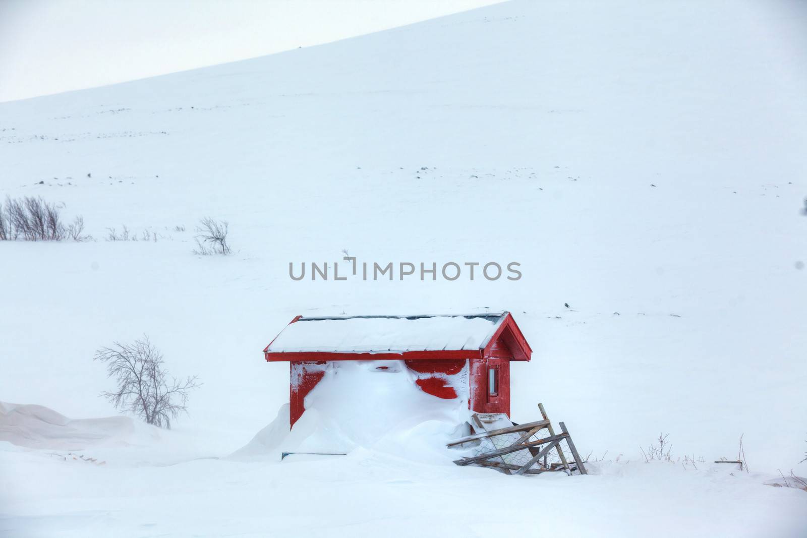 Red wooden Finnish house covered with snow