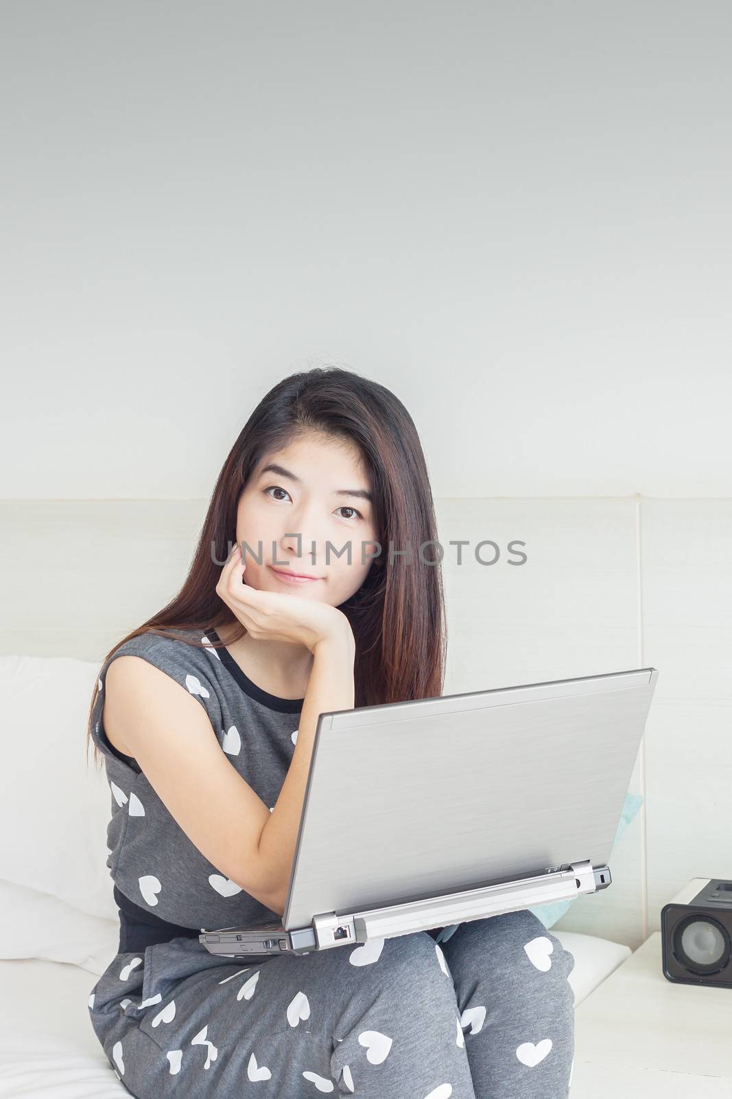 Young Asian woman playing internet on notebook and smile by FrameAngel