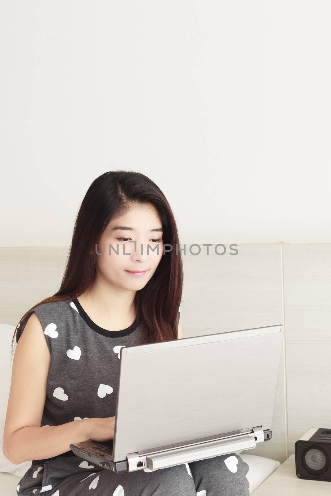 Young Asian woman playing internet on notebook and smiling