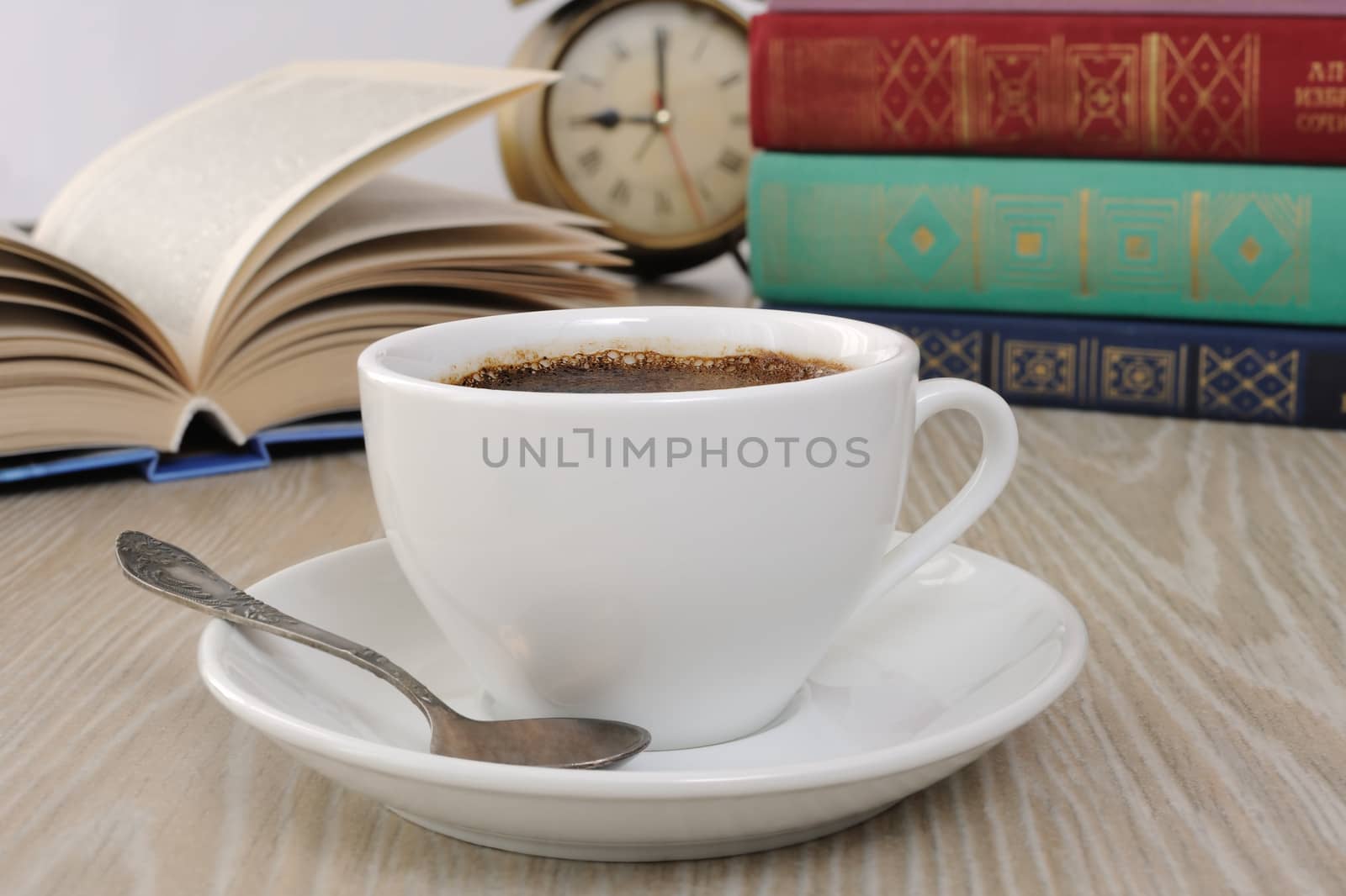 A cup of fragrant black coffee on the table against the background of an open book

