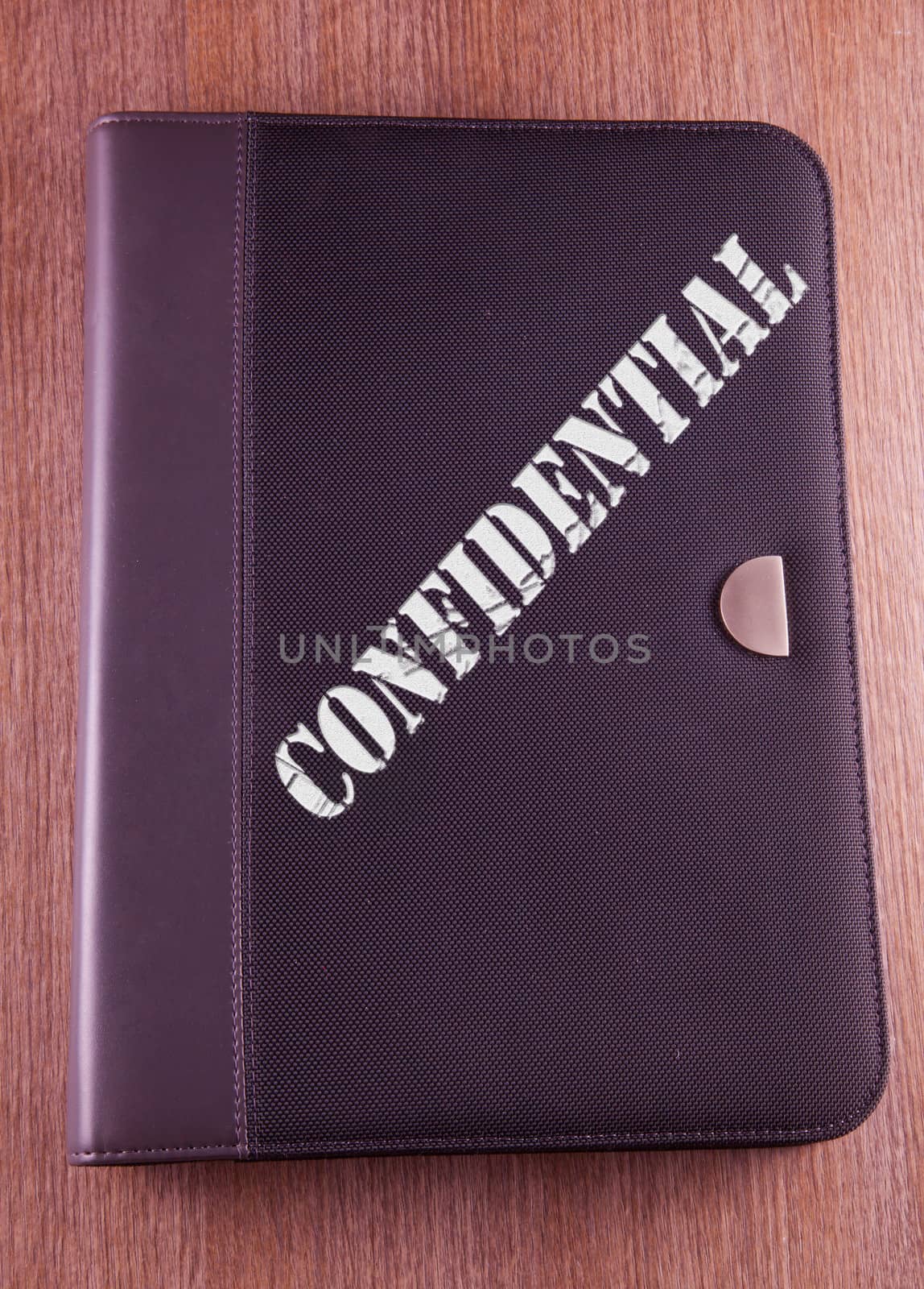 Gray folder over wooden background, with text "Confidential" over it