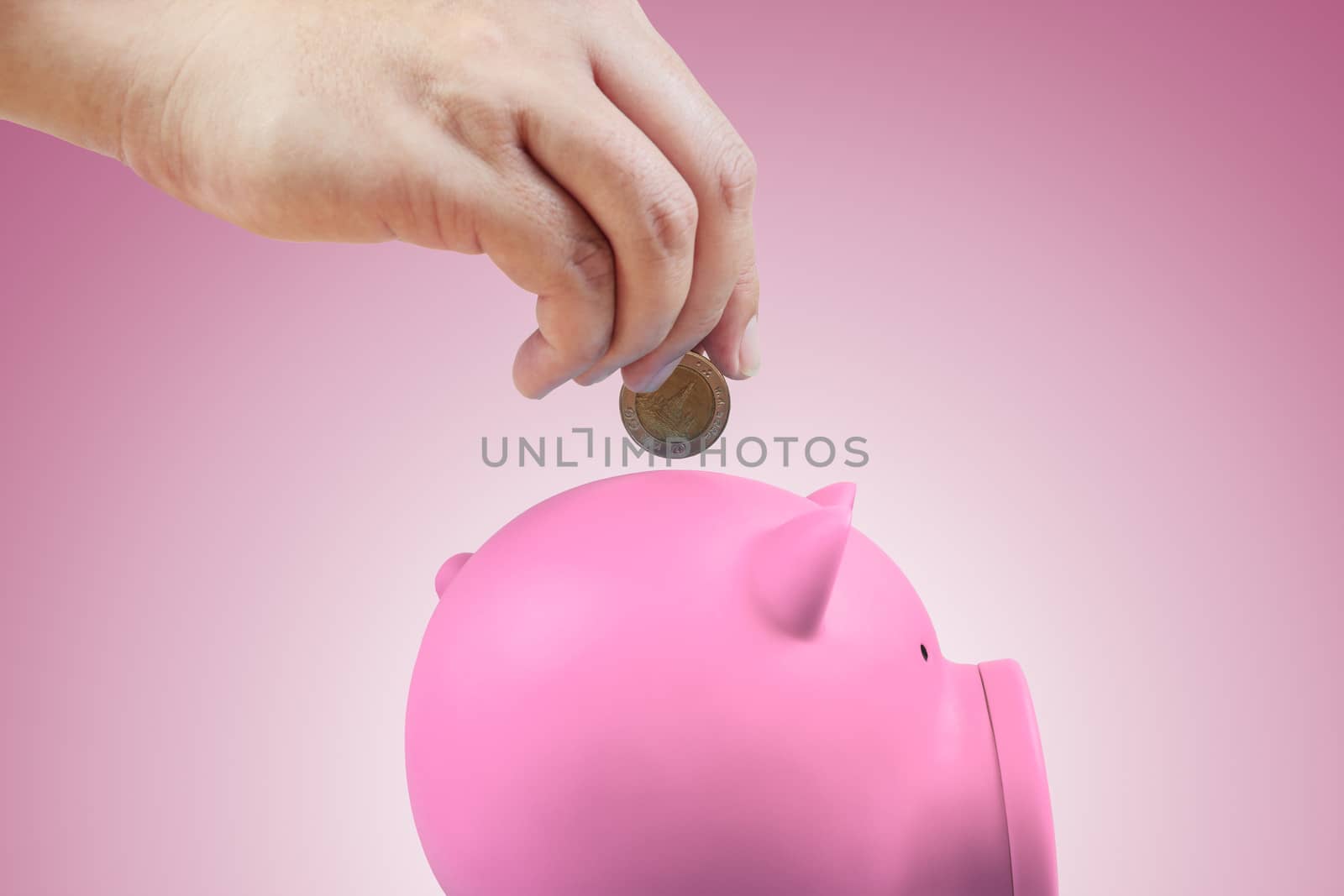 Saving money, hand putting coin into piggy bank