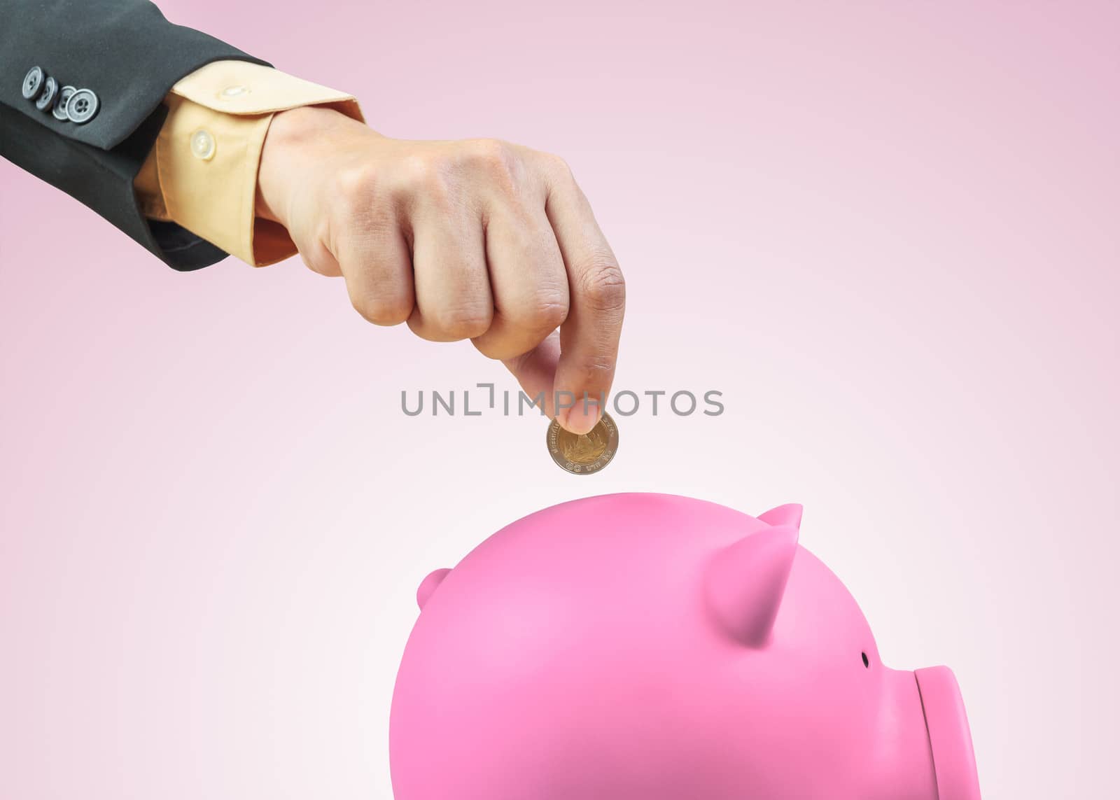 Saving money, hand putting coin into piggy bank
