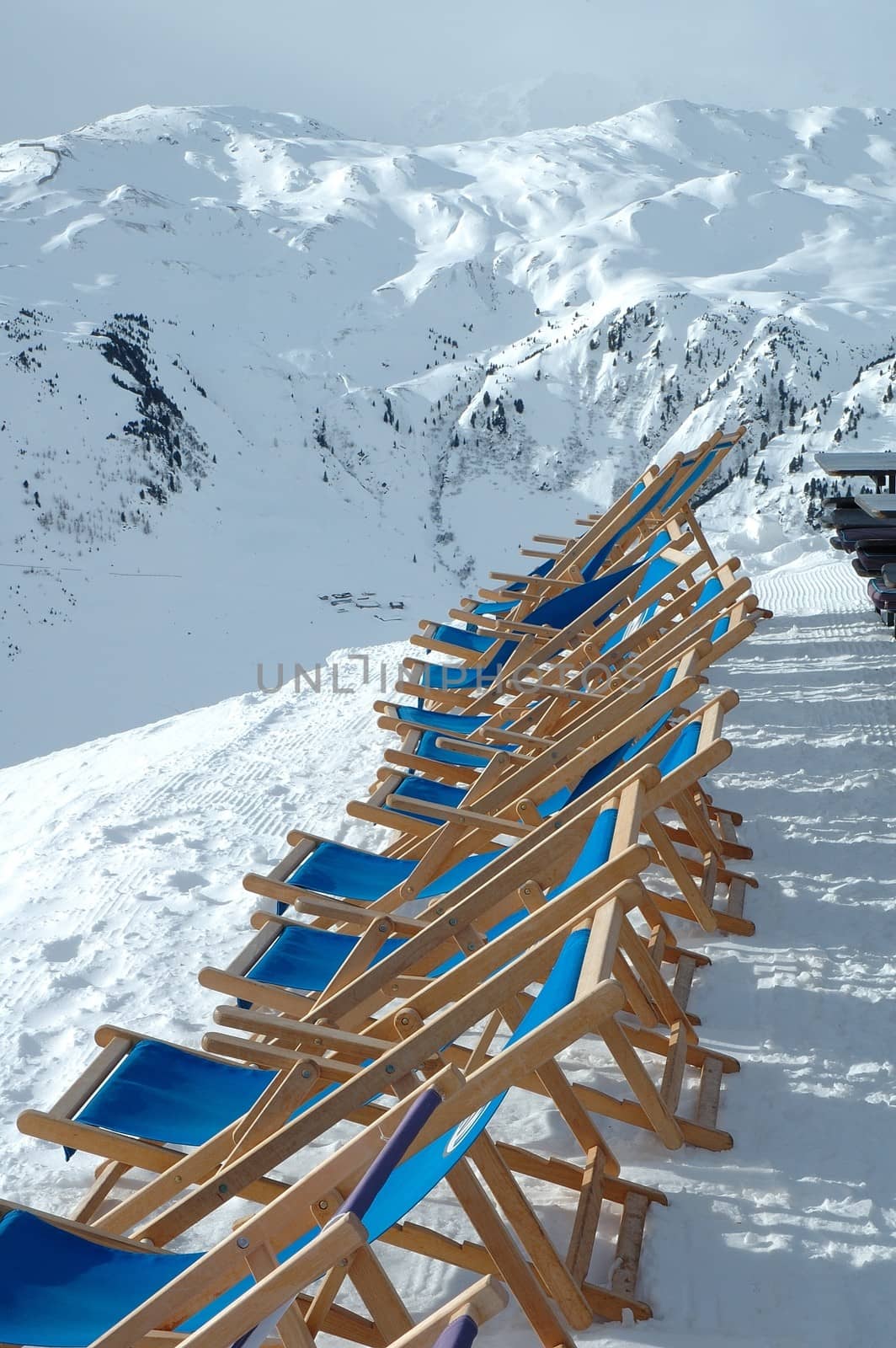 Deckchairs on peak in Alps in winter by janhetman