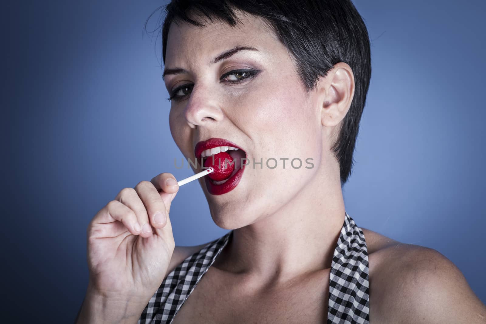 Eat, happy young woman with lollypop in her mouth on blue background