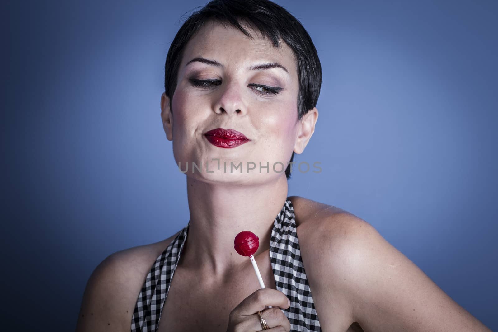 Sexy happy young woman with lollypop in her mouth on blue background