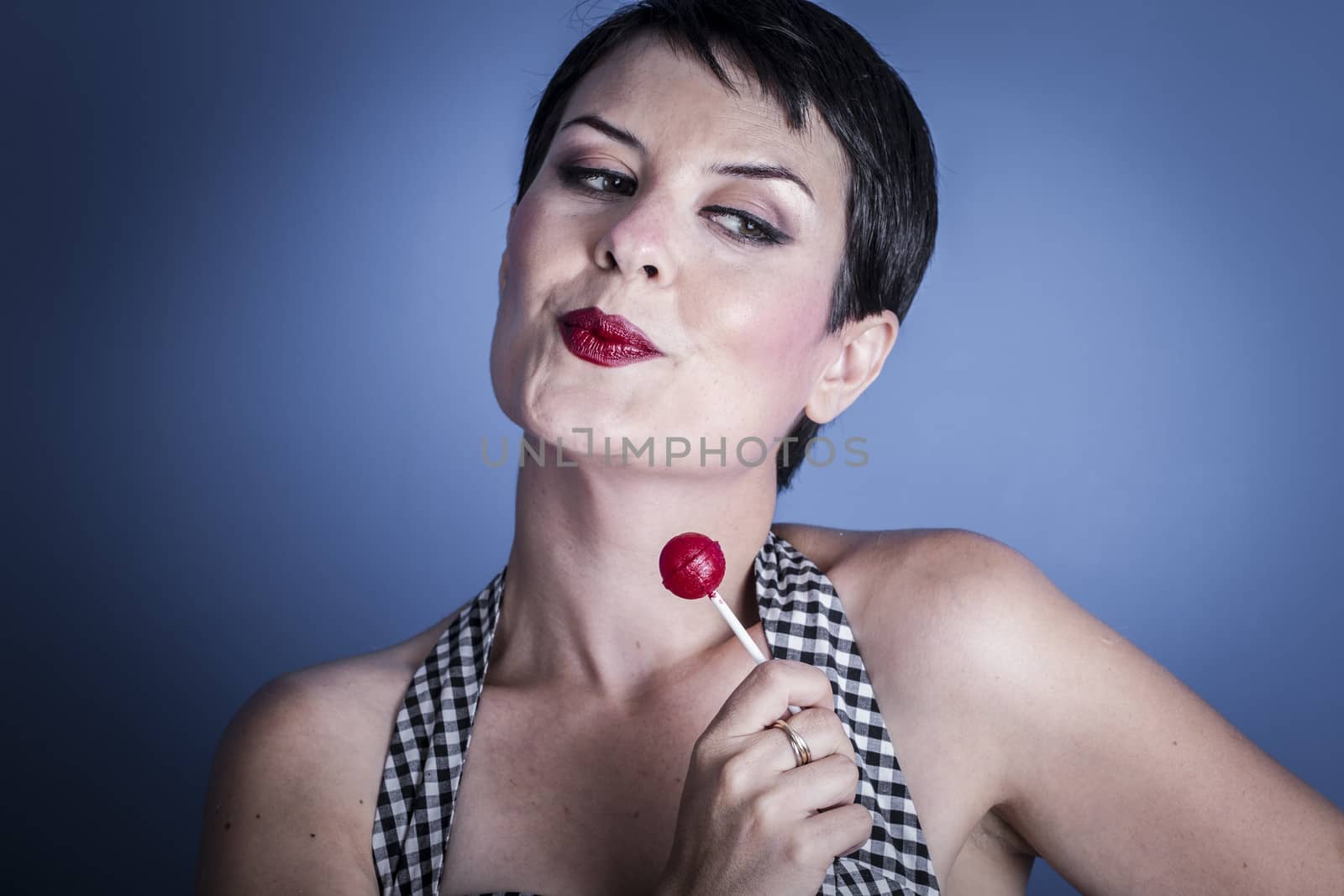 Sexy happy young woman with lollypop in her mouth on blue background