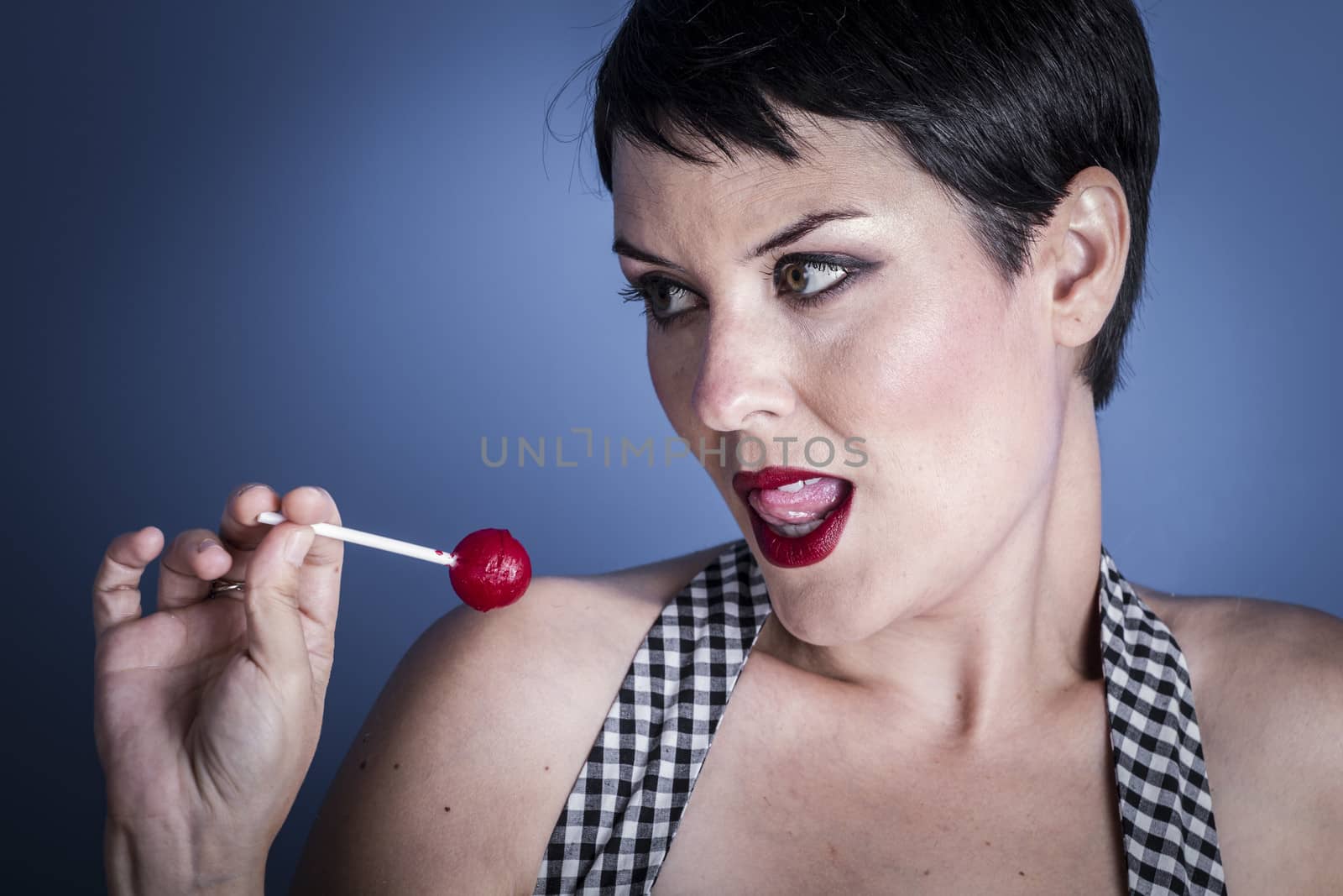 Diet, happy young woman with lollypop in her mouth on blue background