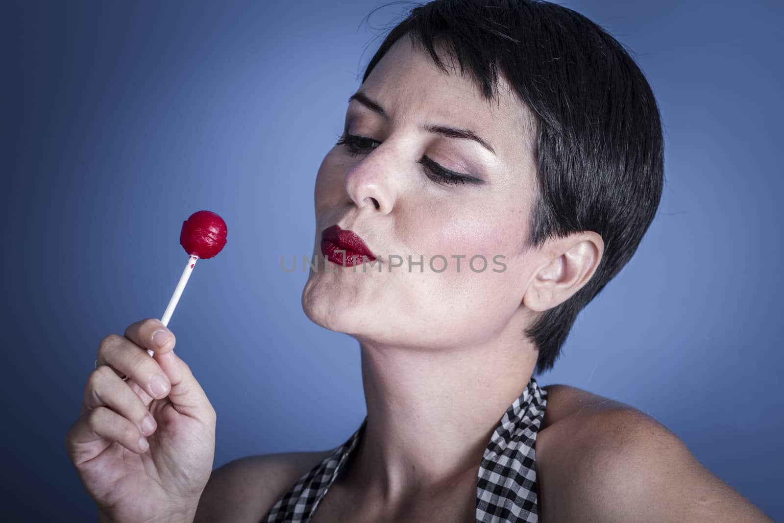 Candy, happy young woman with lollypop in her mouth on blue bac by FernandoCortes