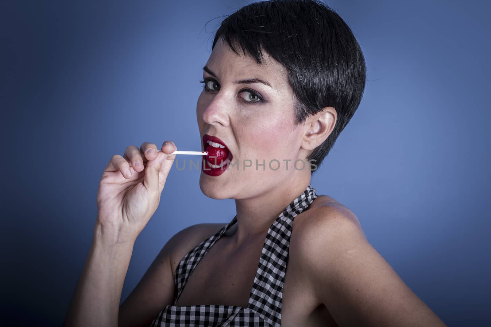Candy, happy young woman with lollypop in her mouth on blue background