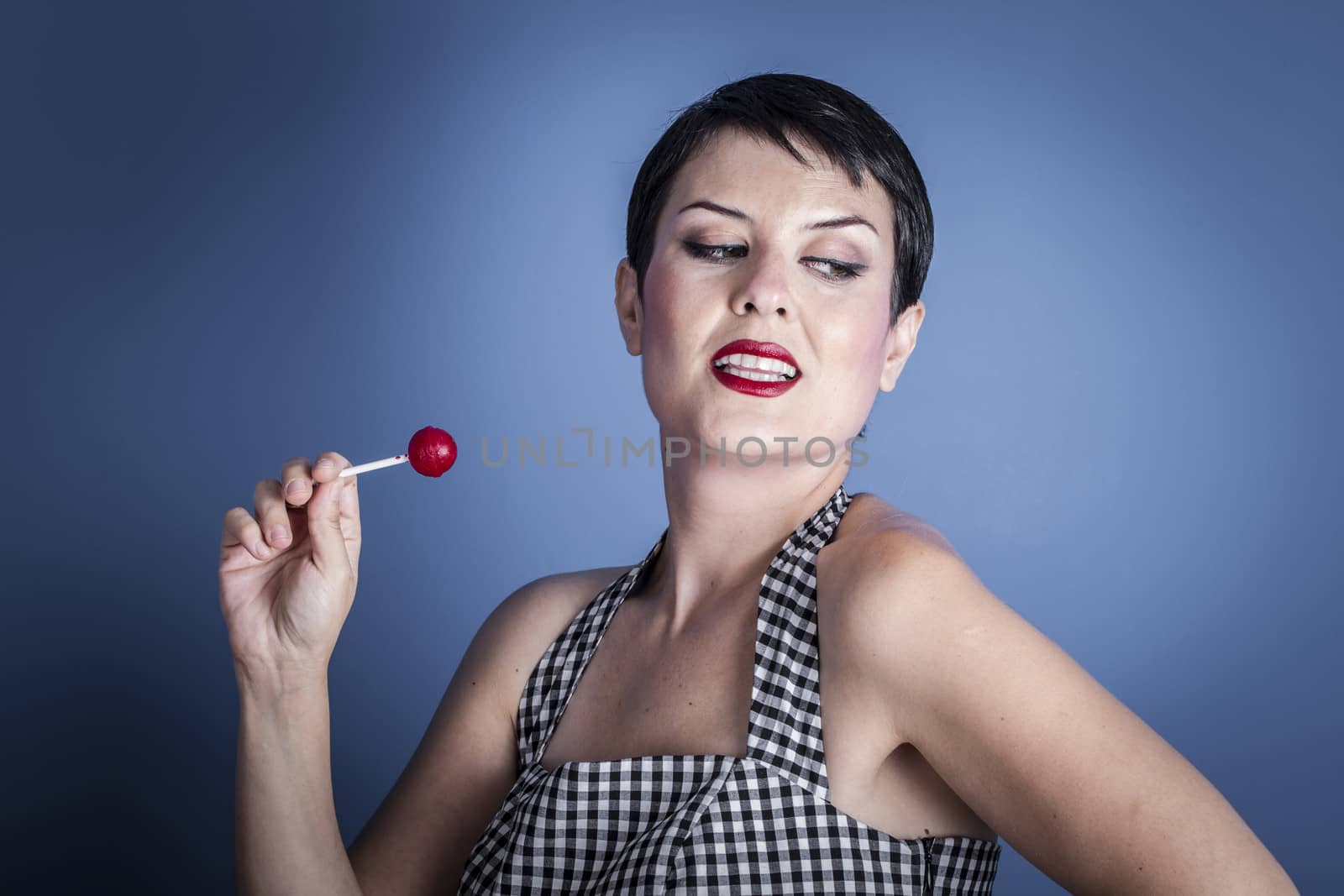 Eat, happy young woman with lollipop in her mouth on blue background