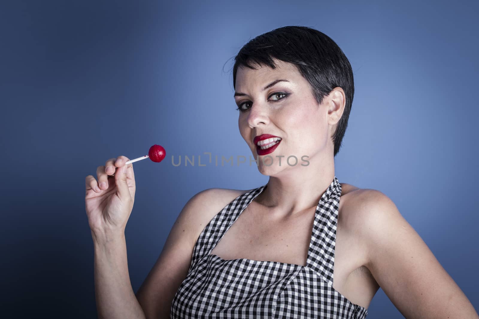 Candy, happy young woman with lollypop in her mouth on blue background