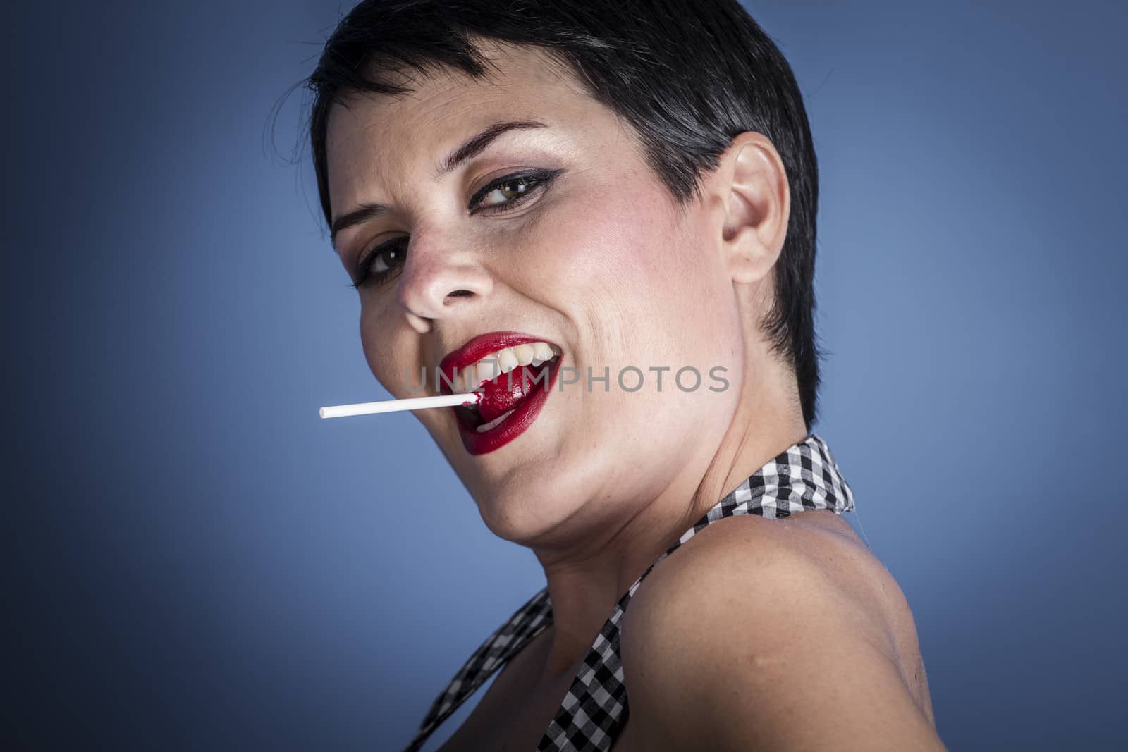 happy young woman with lollypop in her mouth on blue background by FernandoCortes