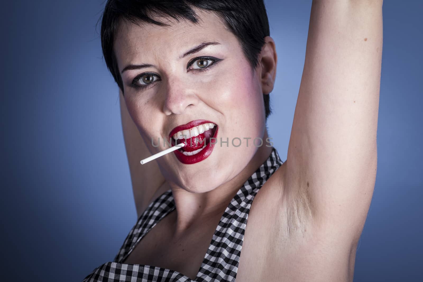 happy young woman with lollypop in her mouth on blue background