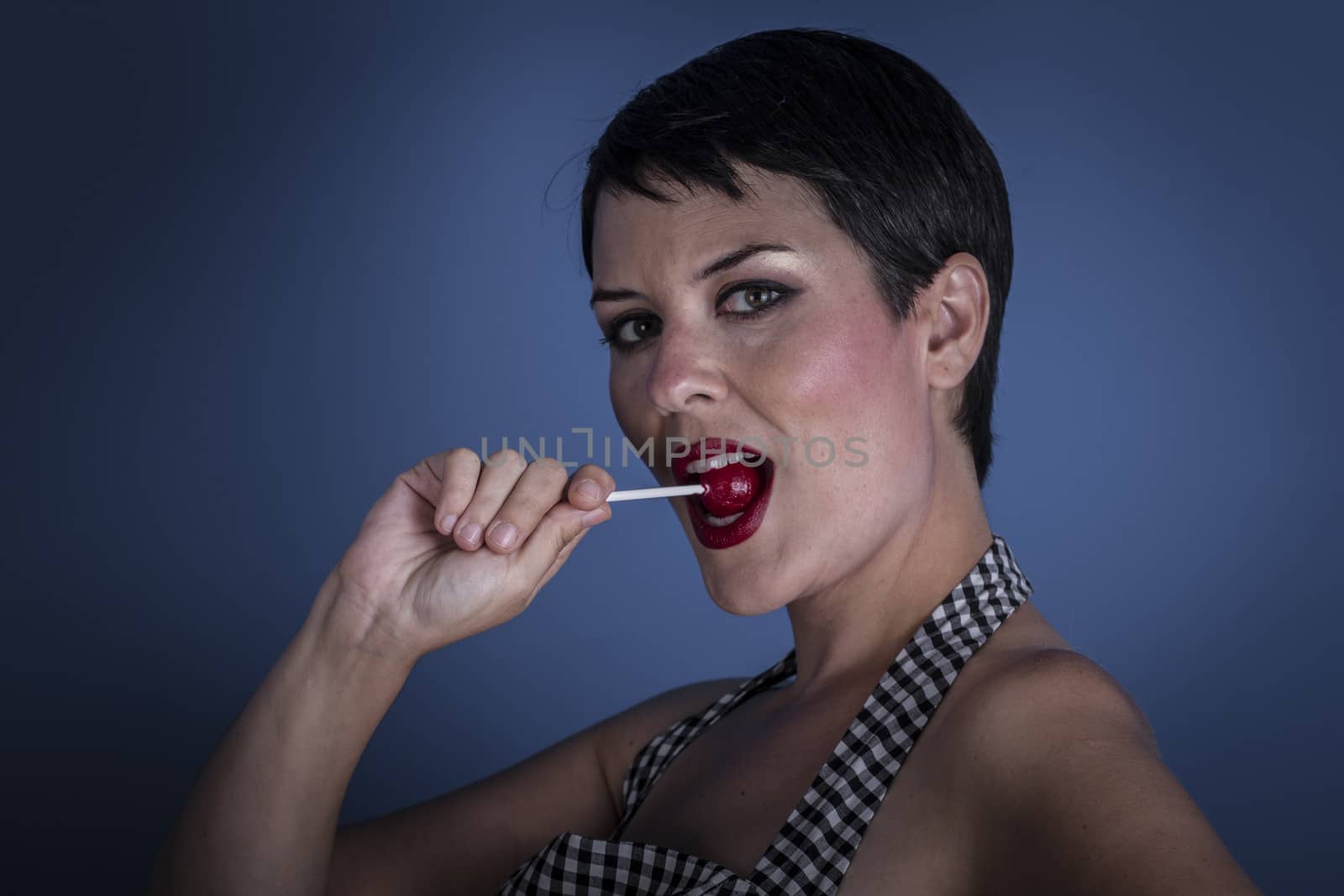 happy young woman with lollypop in her mouth on blue background