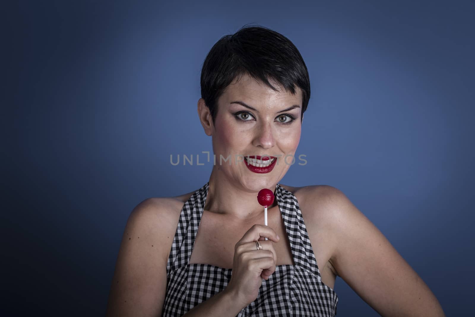 Diet, happy young woman with lollypop in her mouth on blue background
