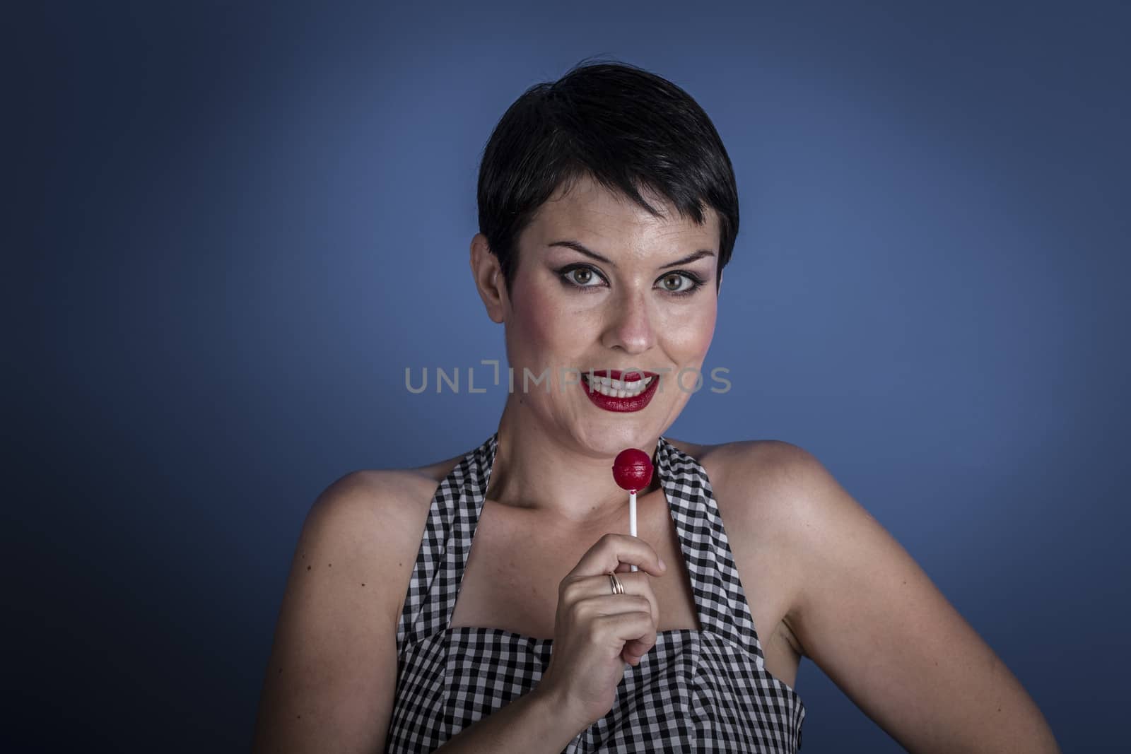 Diet, happy young woman with lollypop in her mouth on blue back by FernandoCortes