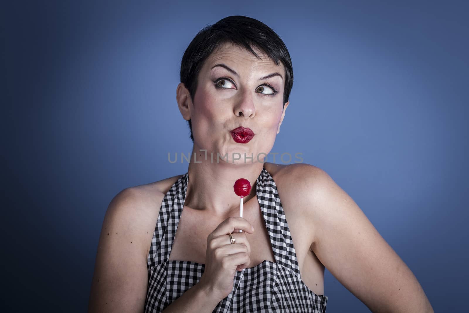 Lolly, happy young woman with lollypop in her mouth on blue bac by FernandoCortes