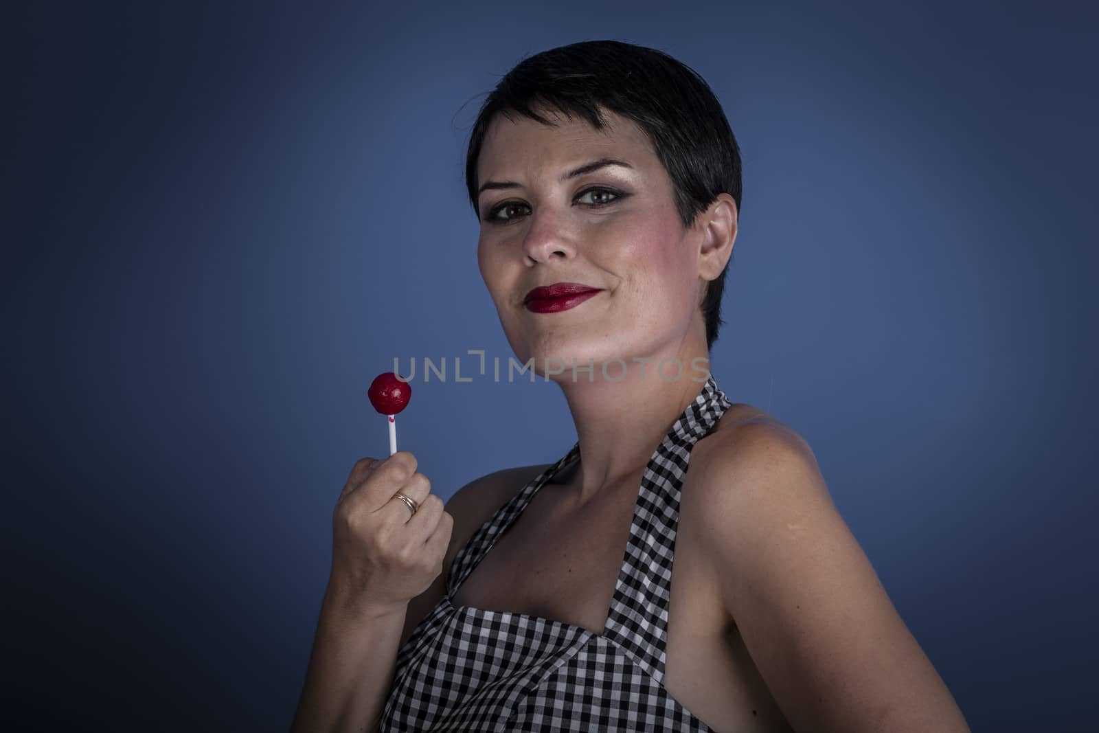 happy young woman with lollypop in her mouth on blue background