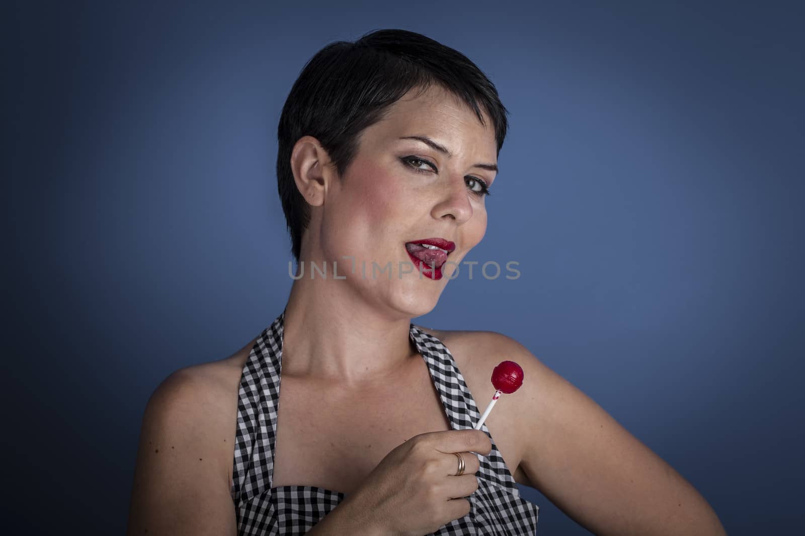 happy young woman with lollypop in her mouth on blue background by FernandoCortes