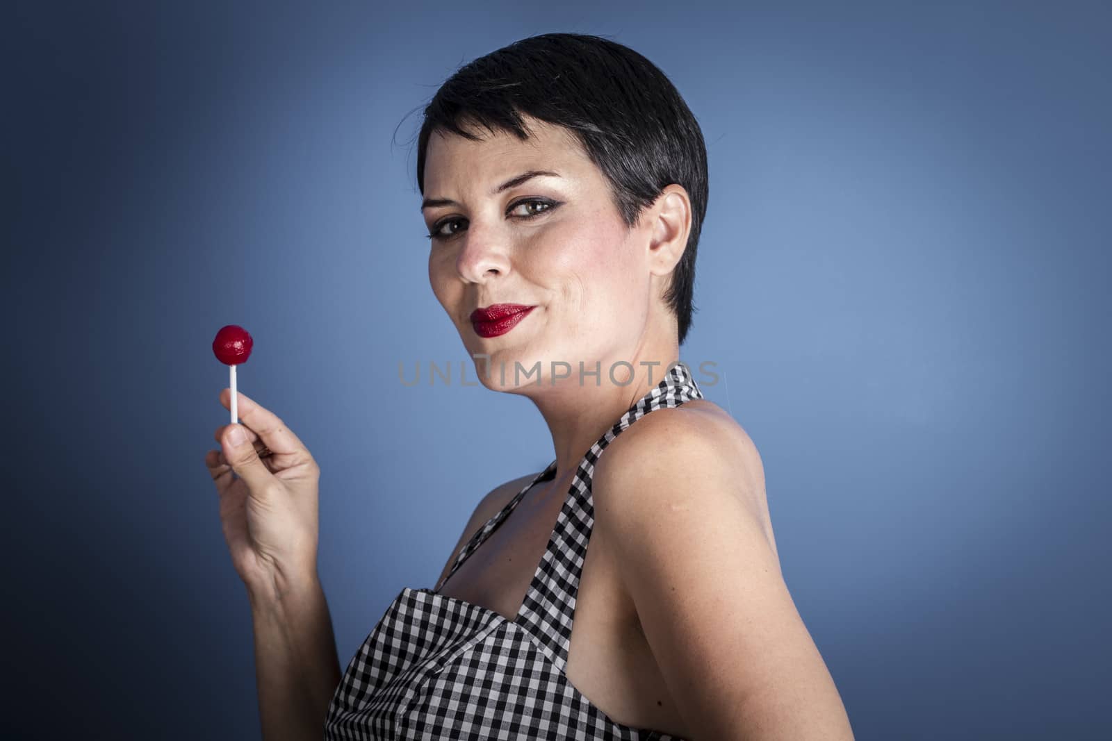 happy young woman with lollipop in her mouth on blue background by FernandoCortes