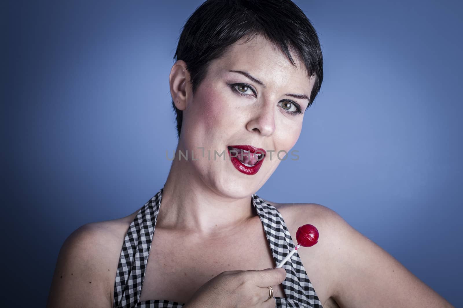 happy young woman with lollypop in her mouth on blue background