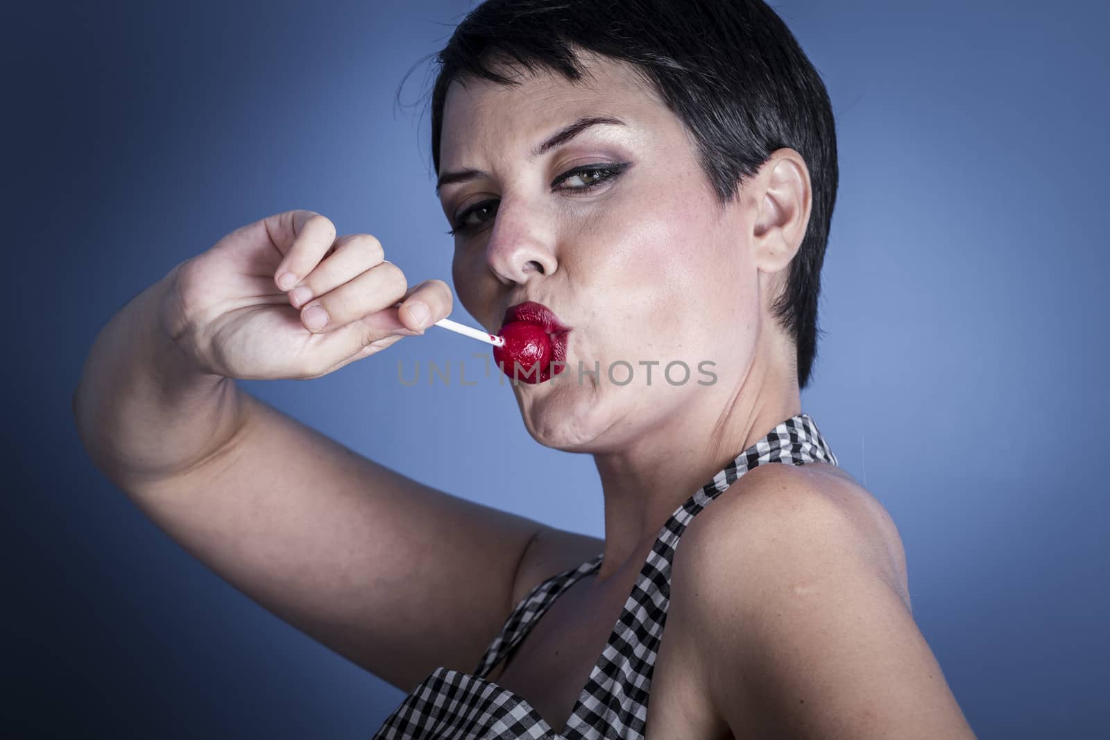 happy young woman with lollypop in her mouth on blue background