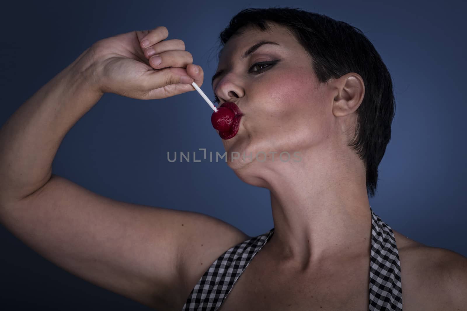 happy young woman with lollypop in her mouth on blue background by FernandoCortes