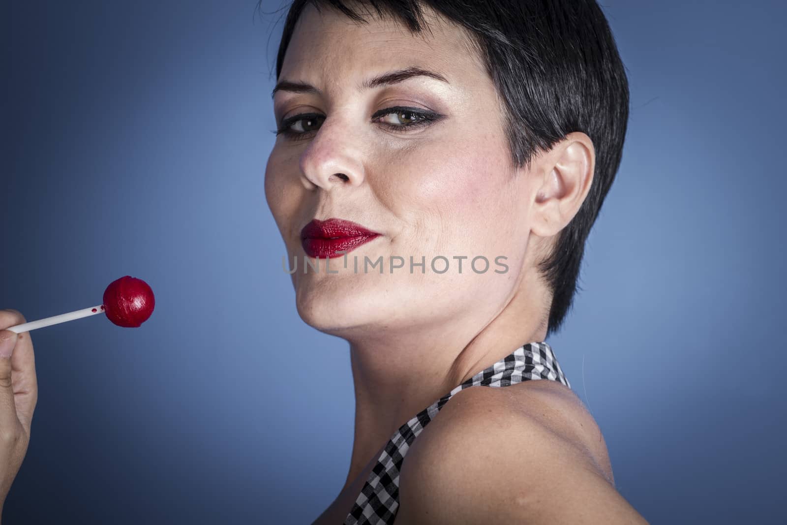 Diet, happy young woman with lollypop in her mouth on blue background