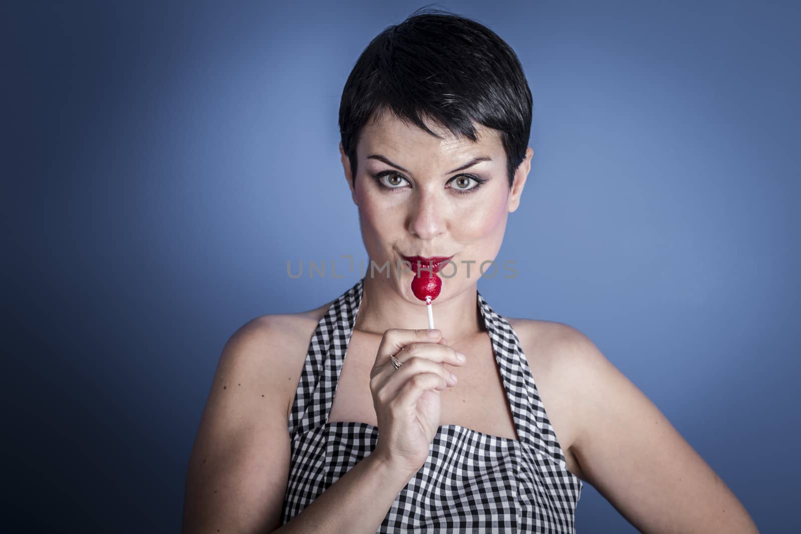 happy young woman with lollypop in her mouth on blue background