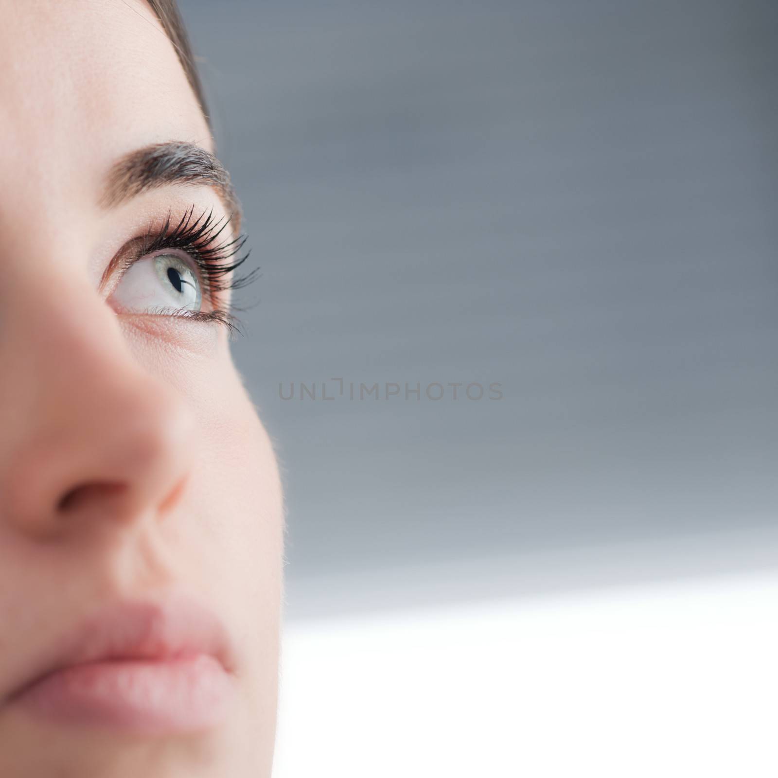 Young attractive blue eyed woman thinking close up.