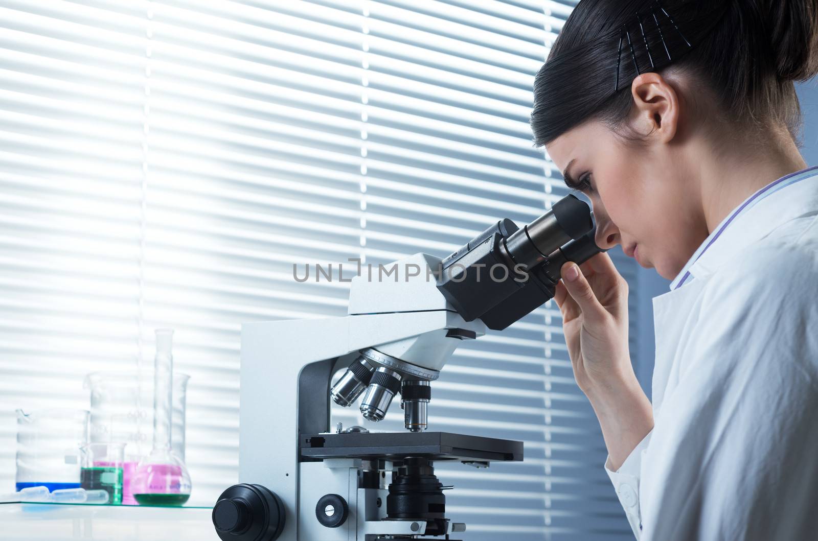 Female researcher using microscope by stokkete