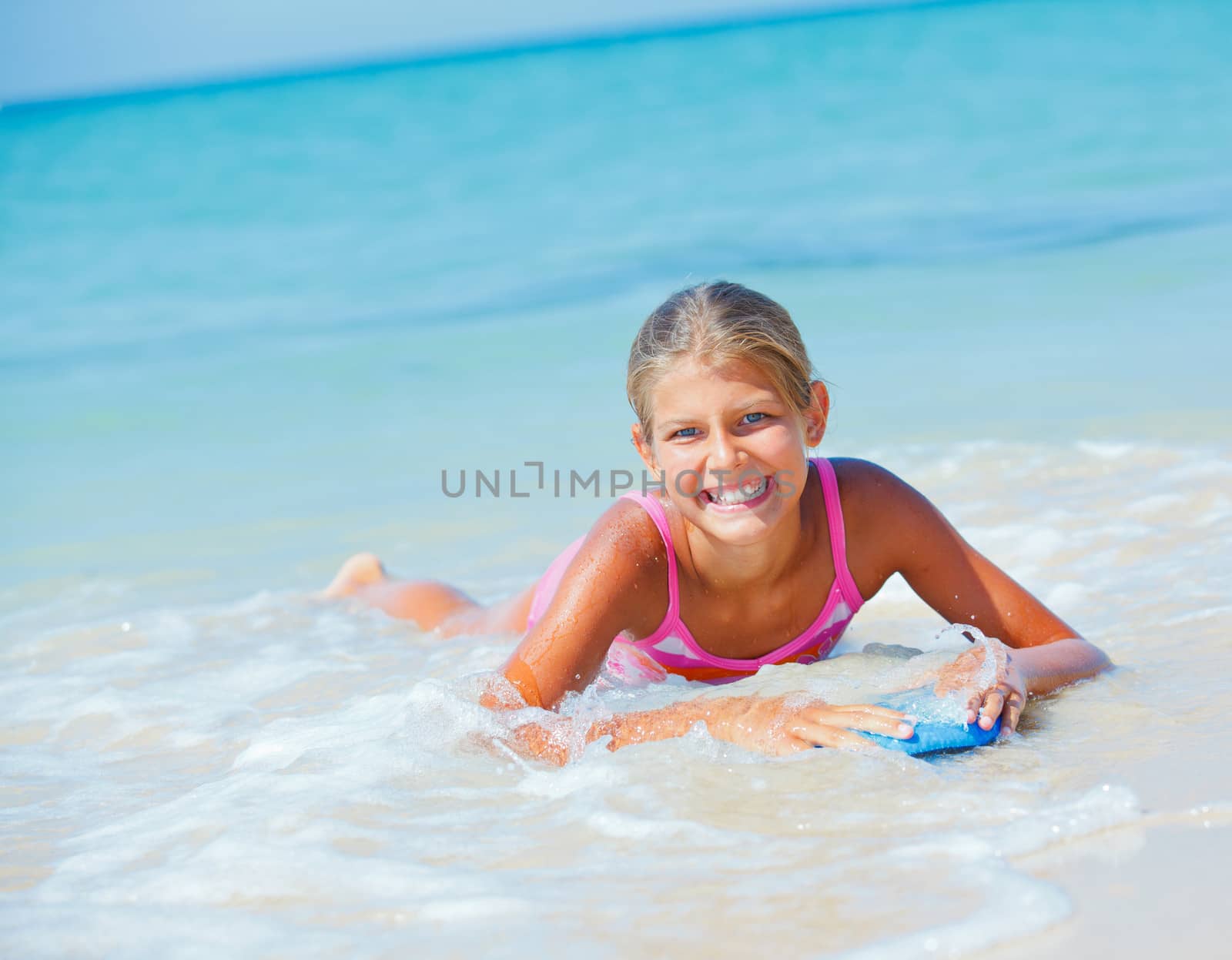 Summer vacation - Happy cute girl having fun with surfboard in the ocean