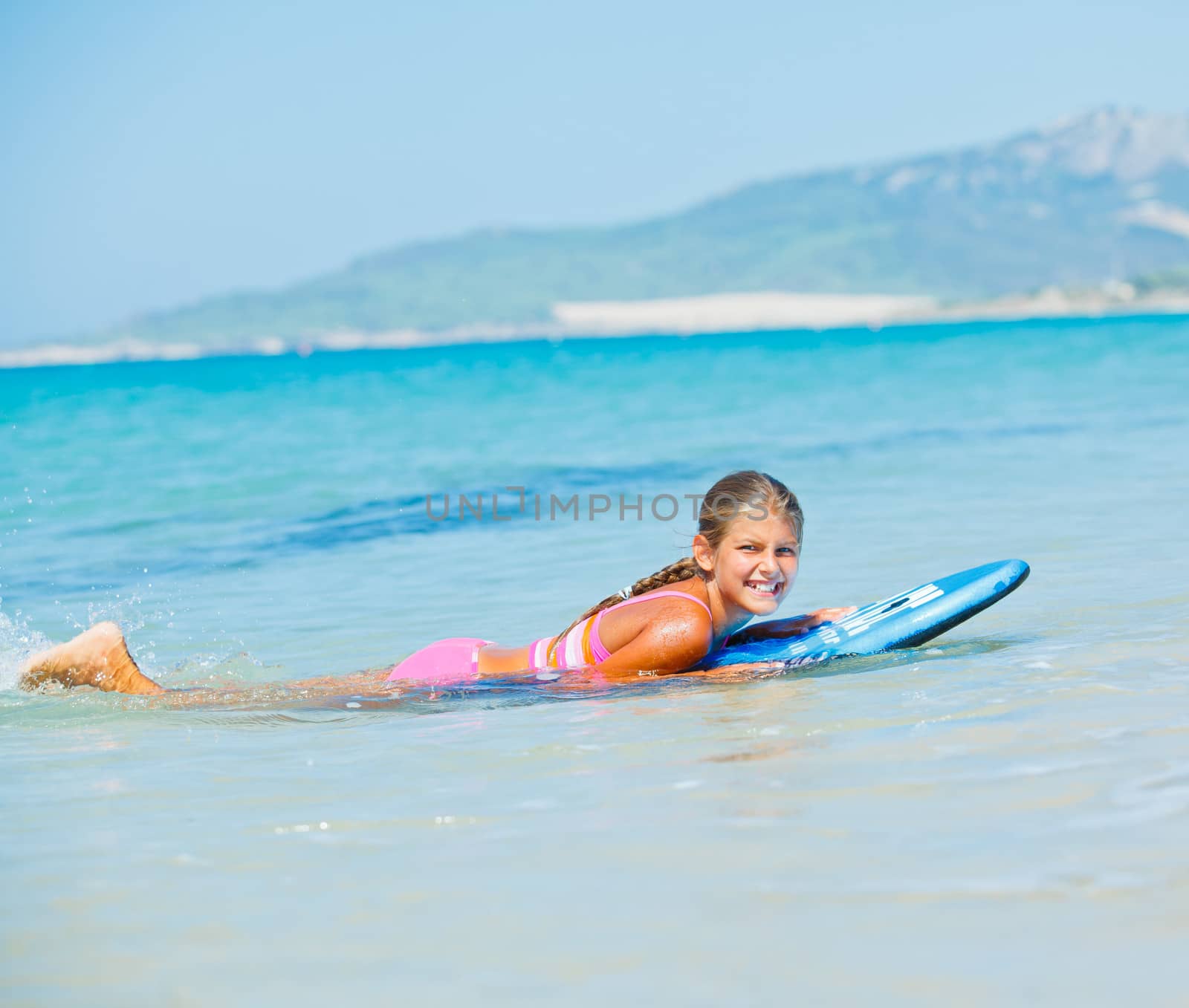 Summer vacation - Happy cute girl having fun with surfboard in the ocean