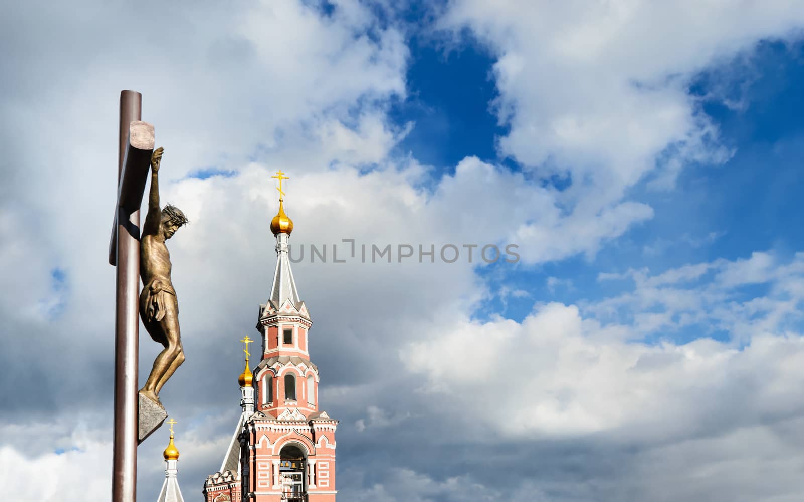 Statue of the crucifixion and church against a cloudy sky. Dniprodzerzhyns'k, Ukraine.