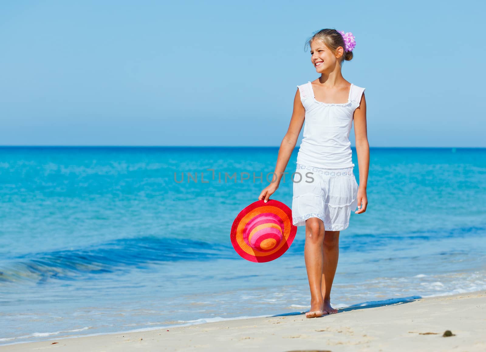 Relaxing beach girl walking with a sun hat at the beach.