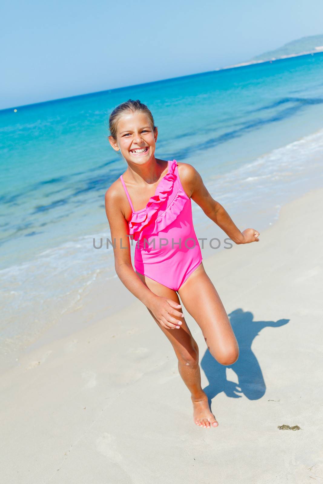 Beautiful happy smiling girl runs along the beach.