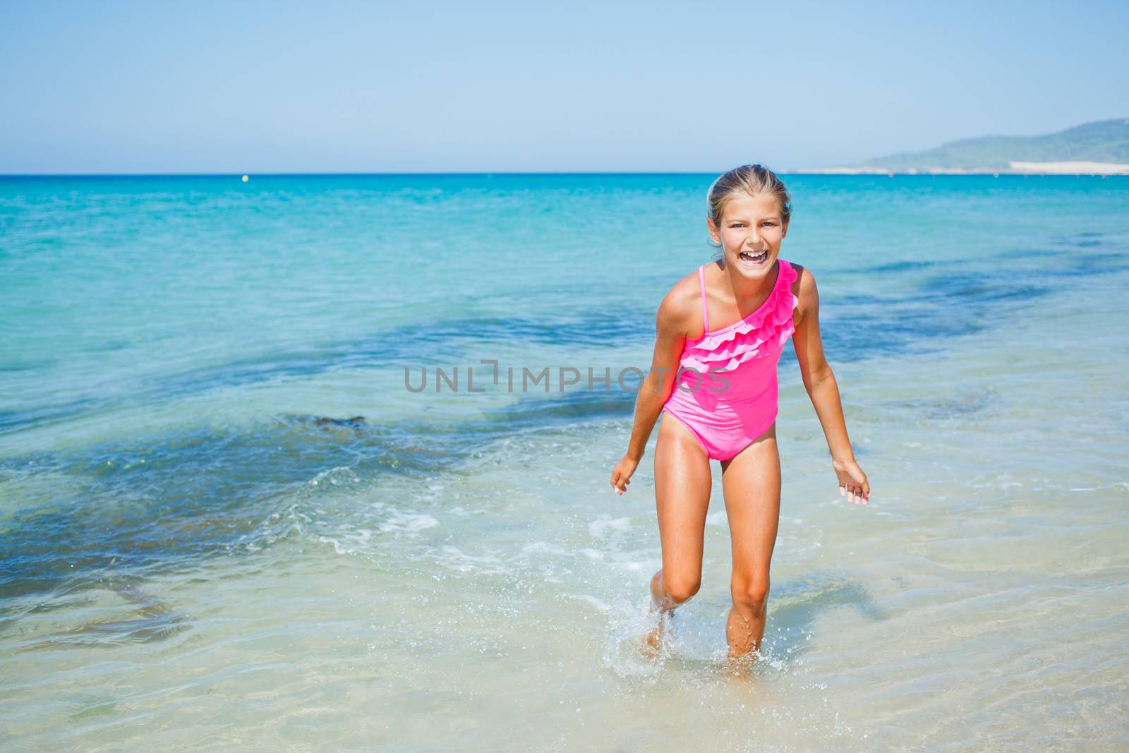 Beautiful happy smiling girl runs along the beach.