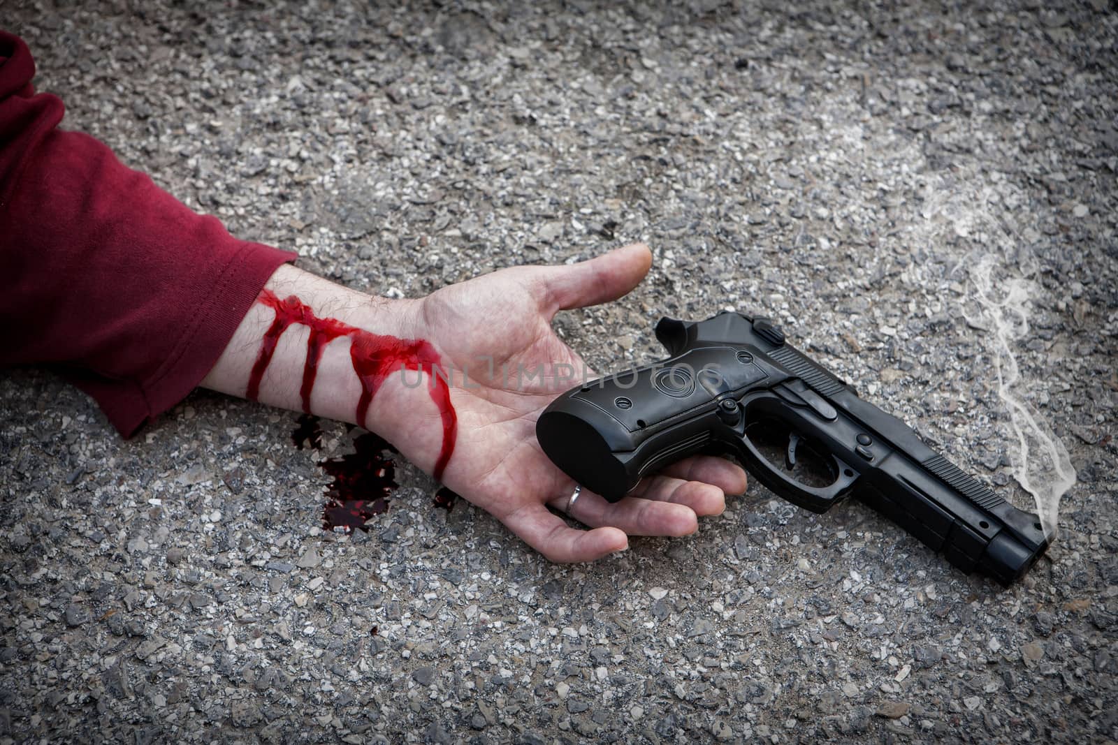 Man with gun in hand bloodstained lies dead in the asphalt murde by digicomphoto