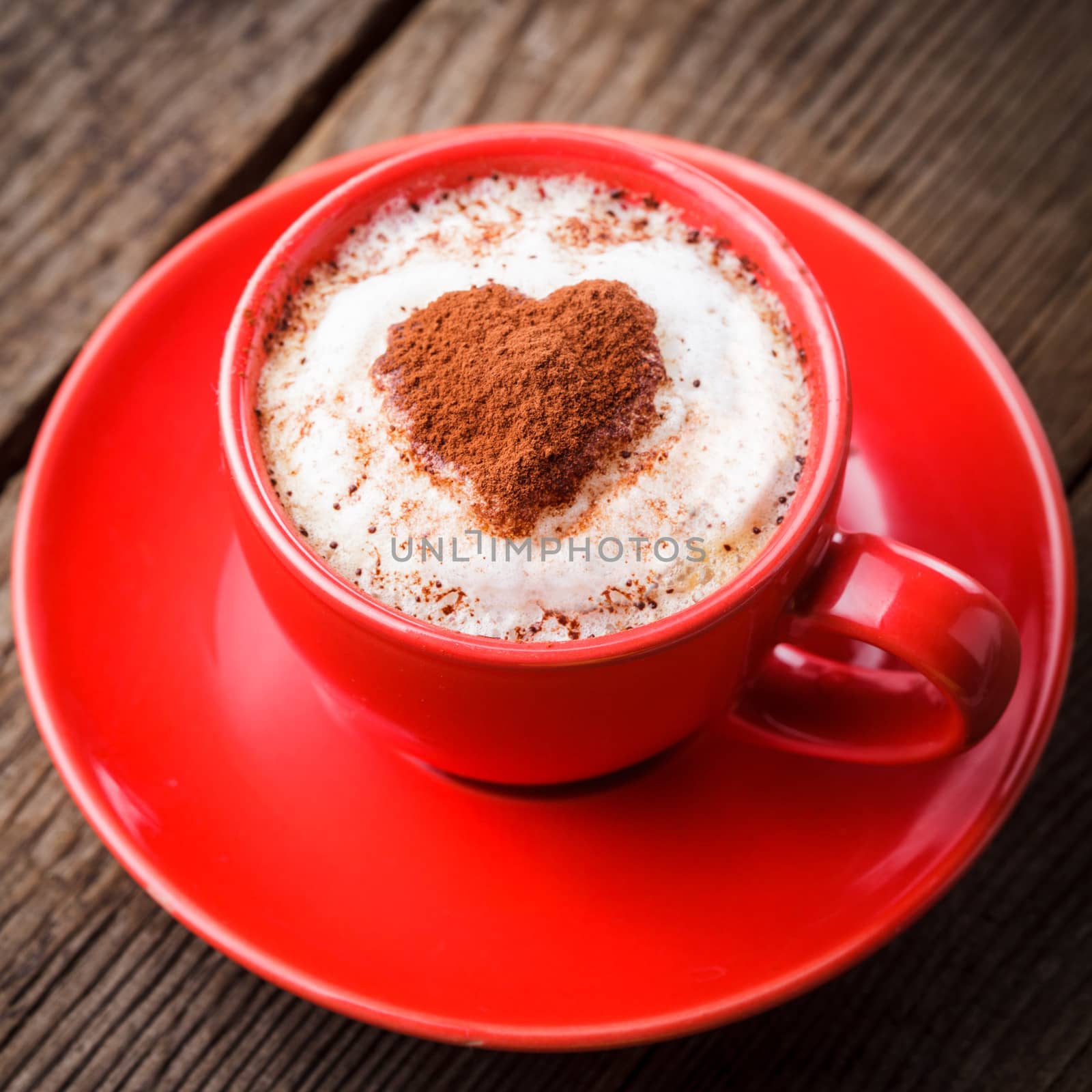 Red cup with cappuccino and heart decoration over foam. Valentine's day cup. Love concept