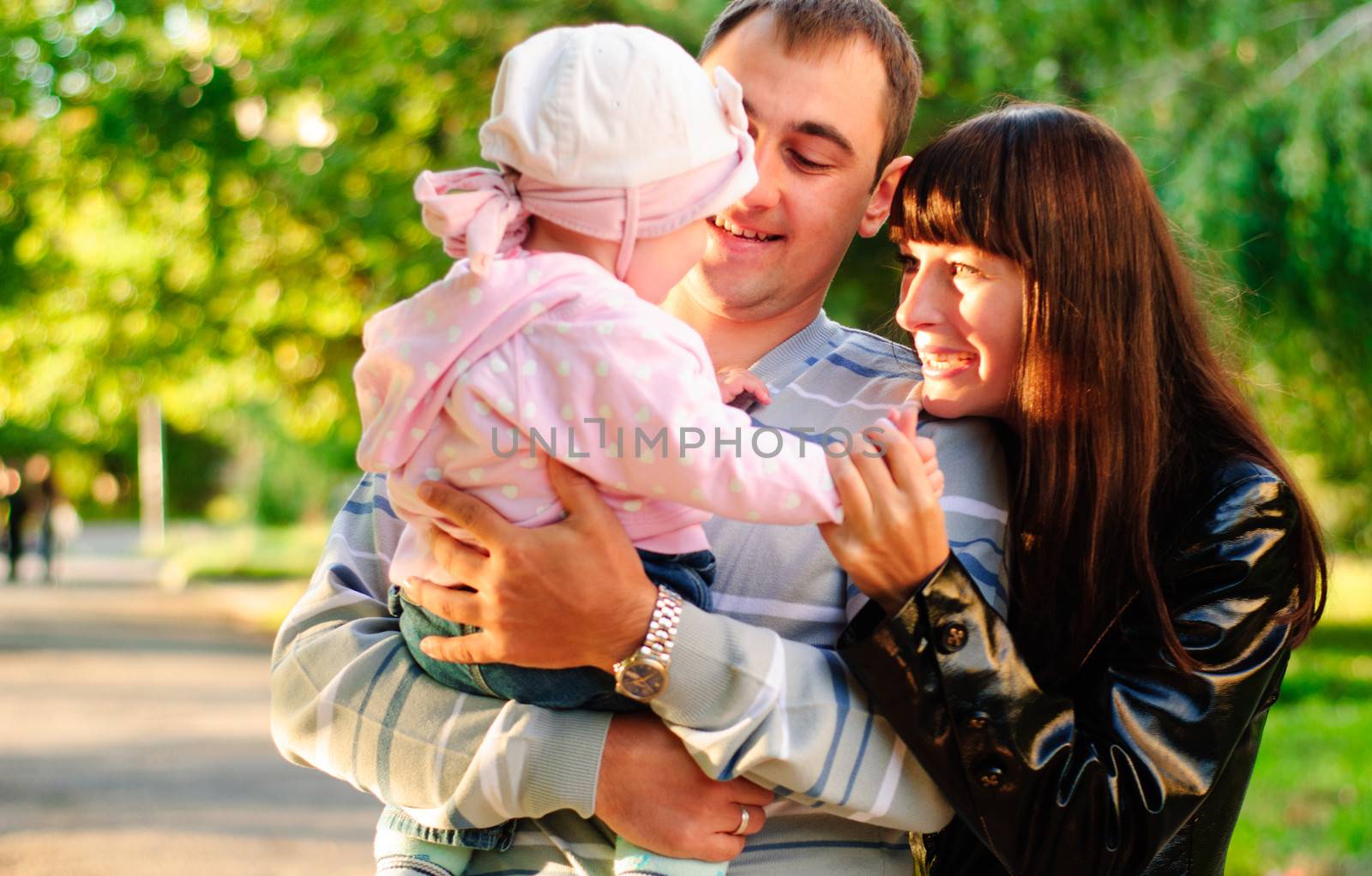 Happy family outdoor - mother, father and daughter are smiling